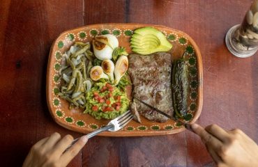 Authentic Mexican meal featuring grilled steak, avocado, and vegetables on a ceramic plate.
